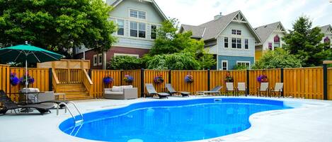 A swimming pool with lounge chairs and a wooden fence.