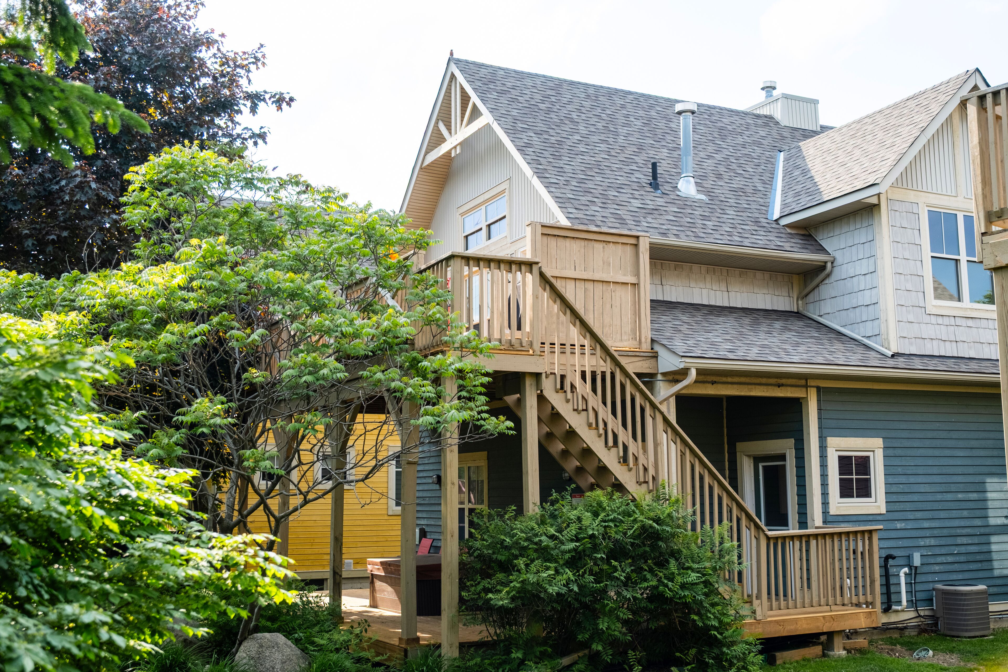 A two-story house with a wooden deck, a staircase, and a porch.