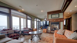 A spacious living room with a fireplace, comfortable seating, and large windows offering a view. - Blue View Chalets (The Blue Mountains)