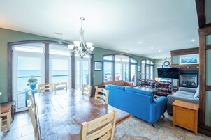 A spacious living area with a large wooden dining table, blue sofa, and a television.