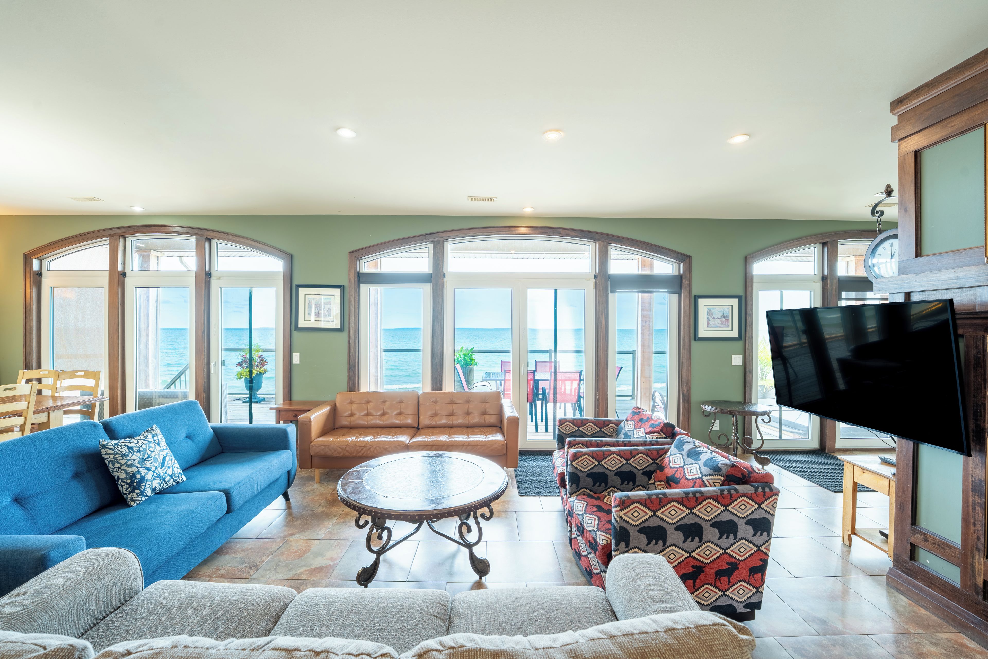 A spacious living room with a blue sofa, a brown leather couch, and patterned armchairs.
