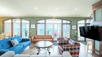 Un salón amplio con un sofá azul, un sofá de cuero marrón y sillones con estampado.