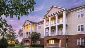 A multi-story residential building with a brick facade, multiple balconies, and a well-maintained lawn.