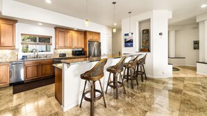 A modern kitchen with wooden cabinets, stainless steel appliances, and a large island with bar stools.