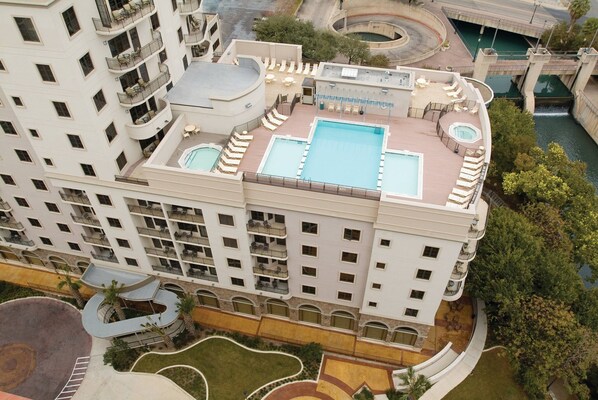 A high-rise hotel with multiple balconies, a rooftop pool, and a landscaped courtyard.