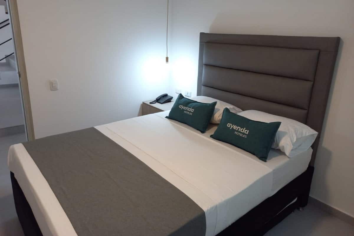 Een hotelkamer met een bed, nachtkastje en lamp.