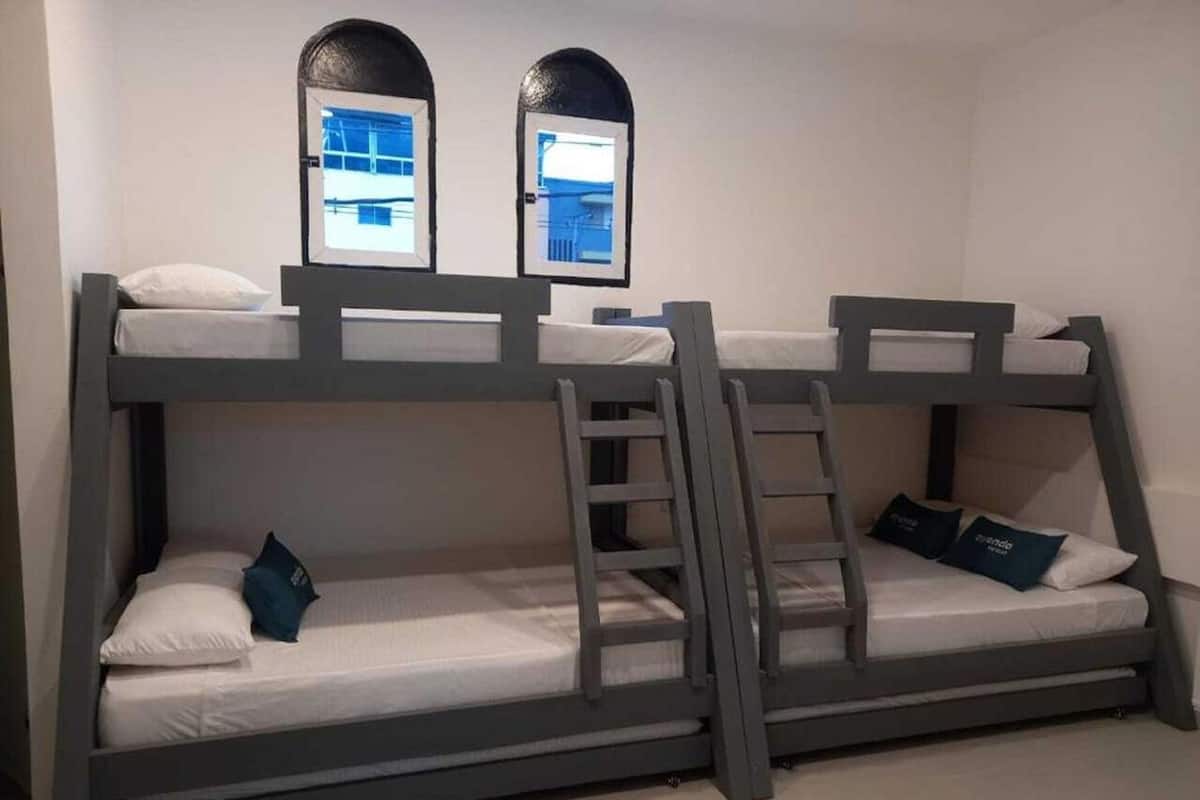 Een slaapkamer met een stapelbed, twee ramen en kussens.