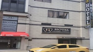 Un bâtiment d'hôtel avec une enseigne indiquant « HÔTEL COLOMBIA AVENIDA » et une voiture jaune garée devant.