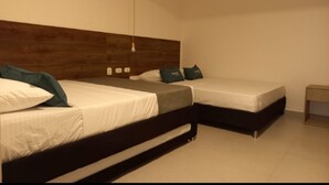 Une chambre avec deux lits, une tête de lit en bois, une table de chevet et un luminaire suspendu.
