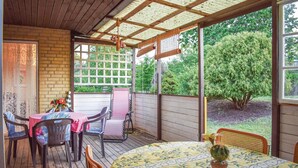 A covered patio with a table and chairs, a wooden fence, and a view of a garden. - Gorgeous home in Hästveda with kitchen (Hästveda)