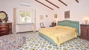 Quarto com cama, cômoda, cadeira, janela e radiador.