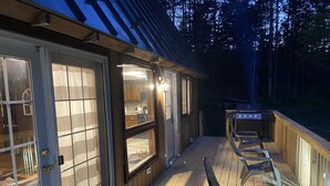 A covered deck with outdoor seating and a barbecue grill.