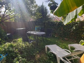 Relax in a serene outdoor space surrounded by lush greenery and a patio area with a round table and four chairs.