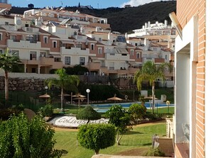 Residents of Colinas del Golf enjoy a resort-like setting with a swimming pool, well-maintained lawns, and palm trees.