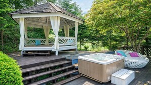 A gazebo with a wooden deck, a hot tub, and outdoor seating. - Greenhill Pension (Pyeongchang)
