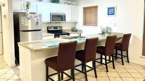 A kitchen with white cabinets, a stainless steel refrigerator, a microwave, a stove, and four brown chairs around a central island. - Simple & Comfortable just like Home - mins walk to Beach - Max 2 Adults + 2 Kids (South Padre Island)