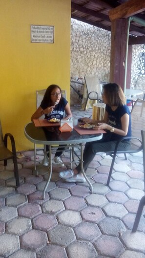 Two people dining at an outdoor table with a stone wall background. - Yucatan Vista Inn (Mérida)