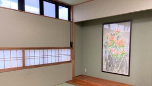 Una habitación japonesa tradicional con suelo de tatami, paneles shoji y un grabado botánico enmarcado en la pared.