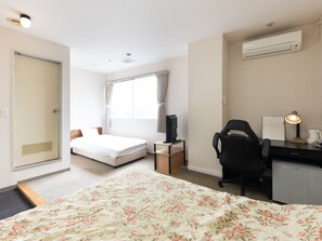 Une chambre d’hôtel comprenant un lit, un bureau avec une chaise, une télévision et un appareil de climatisation.