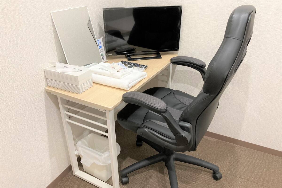 Un espacio de trabajo con escritorio, computadora, silla y unidad de almacenamiento.