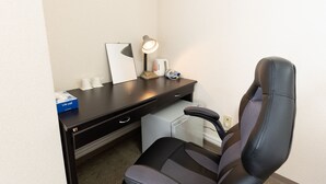 Una habitación de hotel con escritorio, silla y lámpara.