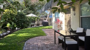 Une terrasse avec un chemin en briques, du mobilier d’extérieur et un espace salon abrité.