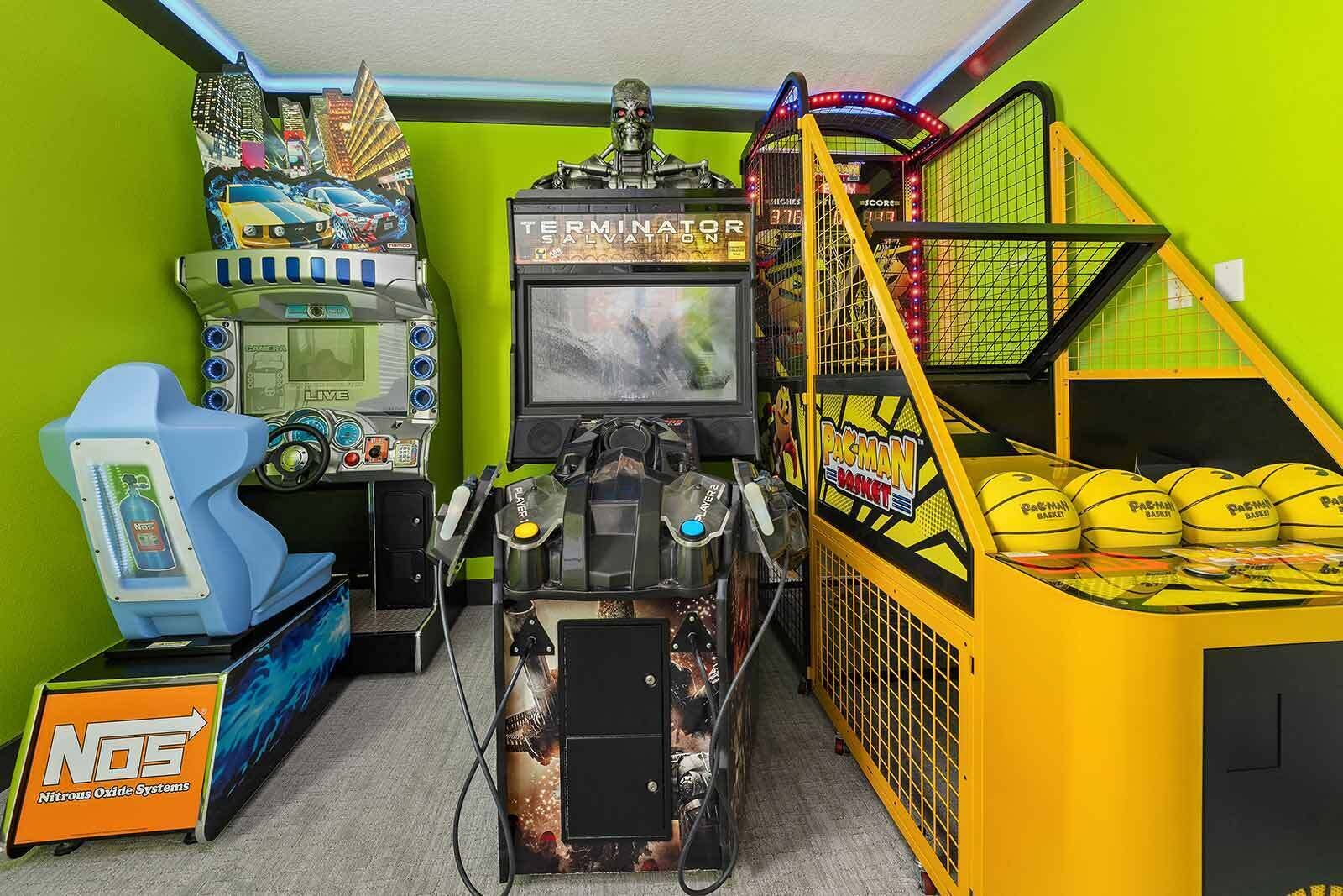 A gaming room with arcade machines, a Pacman arcade, and a basketball hoop.