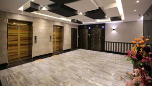 A modern lobby with a marble floor, multiple elevators, and a flower arrangement. - Pohang Jukdosijang Idea Hotel (Pohang)