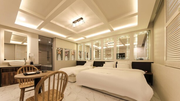 A modern hotel room with a large bed, a desk with a chair, a vanity with a mirror, and a bathroom with a shower. - Pohang Jukdosijang Idea Hotel (Pohang)