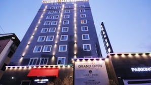 A tall building with multiple windows and a sign for a grand opening. - Pohang Jukdosijang Idea Hotel (Pohang)
