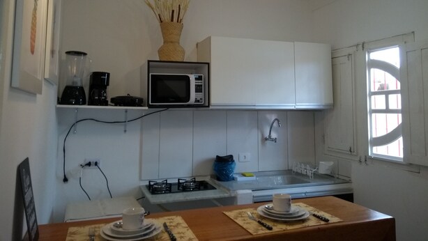 A modern kitchen with white cabinets, a microwave, a gas stove, and a window with bars.
