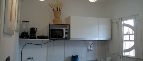 Microondas, cafetera o tetera, utensilios de cocina y mesa de comedor