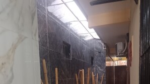 A hallway with marble walls, bamboo plants in pots, and a herringbone patterned floor.