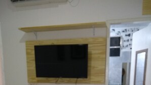 A hotel room with a bed, a television mounted on the wall, and a bathroom visible through an open door.