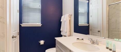 A bathroom with a white sink, a mirror, and a toilet.
