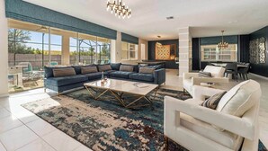 A spacious living room with a sectional sofa, a coffee table, and a dining area with a chandelier.
