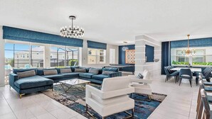 A modern living room with a sectional sofa, a white coffee table, and a dining area with chairs and a table.
