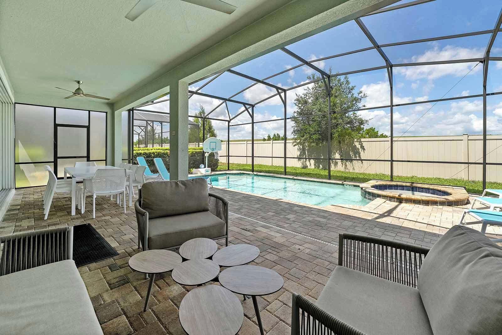 A covered outdoor area with a pool, lounge chairs, and a hot tub.