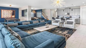 Un salon moderne avec un canapé d’angle, une table basse et un coin repas avec des chaises.