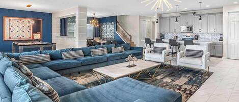 A modern living room with a sectional sofa, a coffee table, and a dining area with chairs.