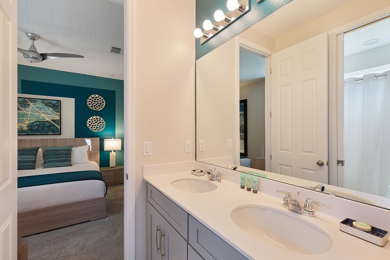A modern bathroom with two sinks, a large mirror, and a ceiling fan.