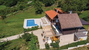 An aerial view of a property with a swimming pool, outdoor seating area, and a building with a red roof.