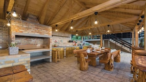 A rustic wooden interior with a kitchen area, wooden dining table, and benches.