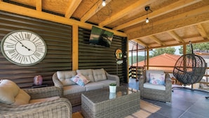 A cozy lounge area with wicker furniture, a large wall clock, and a hanging light fixture.