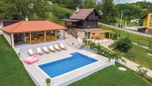 A residential property with a swimming pool, outdoor seating area, and a covered patio.