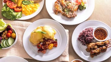 A variety of breakfast dishes including eggs, bacon, and sausages on white plates.