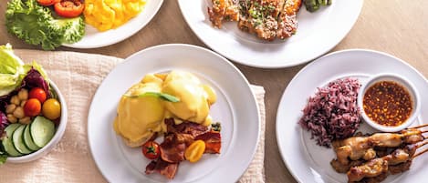 A variety of breakfast dishes including eggs, bacon, and sausages on white plates.