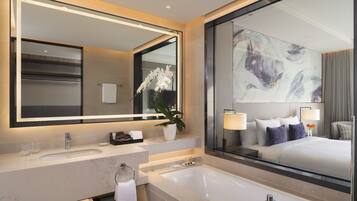 Un baño moderno con un espejo grande, un lavamanos, una bañera y una orquídea en maceta.