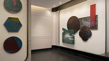 Un corridoio con diverse opere d'arte alle pareti, tra cui elementi circolari ed esagonali.