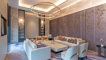 A modern living room with a sectional sofa, armchairs, a coffee table, and a decorative wall with a floral pattern.